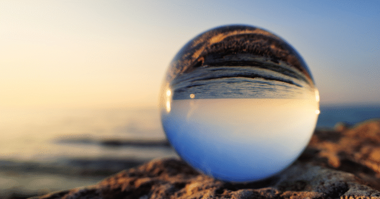 A glass sphere on the beach reflecting the horizon upside down, symbolizing the Law of Correspondence: as within, so without.