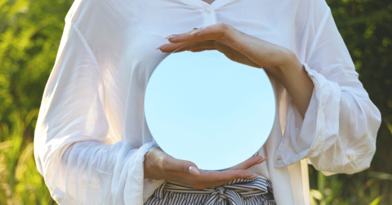 Person holding a circular mirror, symbolizing leadership as a reflection where teams mirror the energy, clarity, and actions of their leader.
